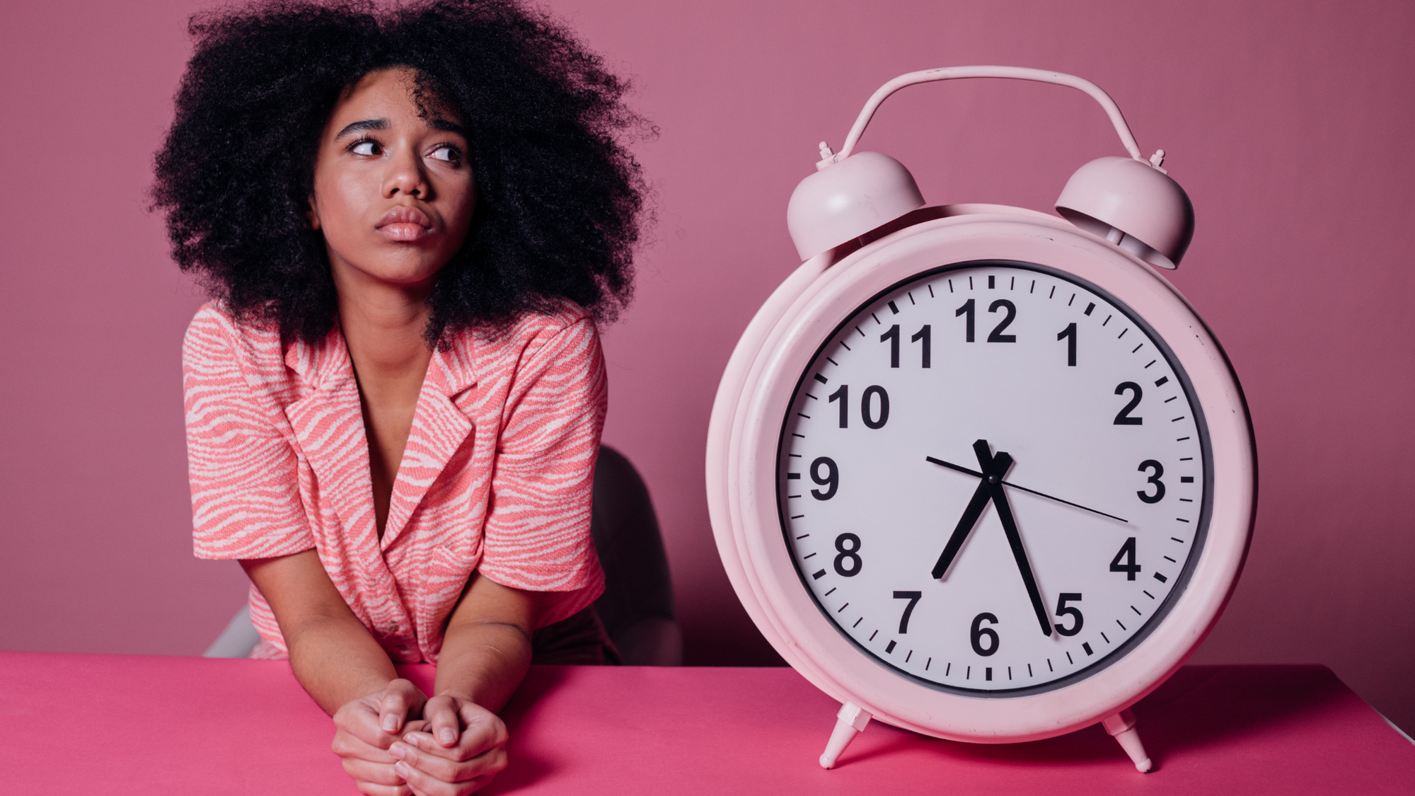 femme à côté d'un réveil qui se demande combien d'heures elle doit dormir